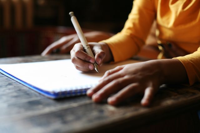 A stock image of a student writing at a school desk.